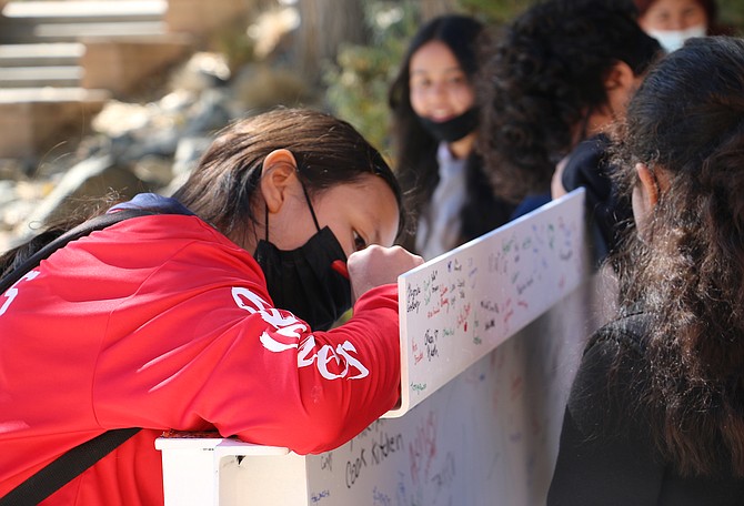 Eagle Valley Middle School eighth grader Yadira Vargas, left, on Tuesday signs a beam for the school’s topping-off ceremony. Jessica Garcia/Nevada Appeal
