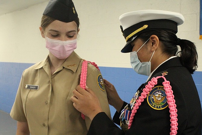 CHS NJROTC cadet Pierrott adjusting an aiguilette on Cadet Baker for the American Breast Cancer Awareness month fundraiser