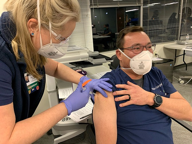 Andrea Burdette, left, ICU nurse director at Northern Nevada Medical Center in Sparks, administers a COVID-19 vaccine to Dr. Robert Dalrymple.