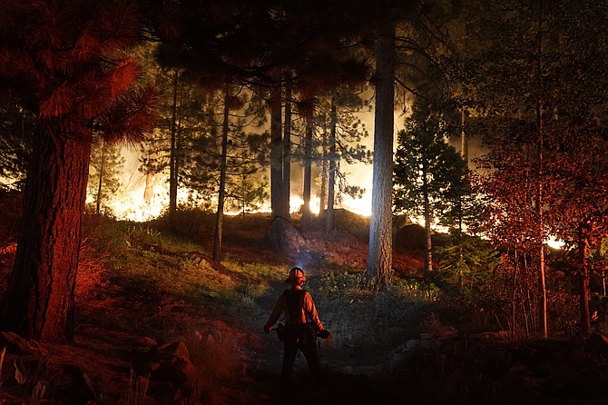 A firefighter monitors the Caldor Fire burning near homes in South Lake Tahoe, Calif., on Aug. 30, 2021. (AP Photo/Jae C. Hong, File)
