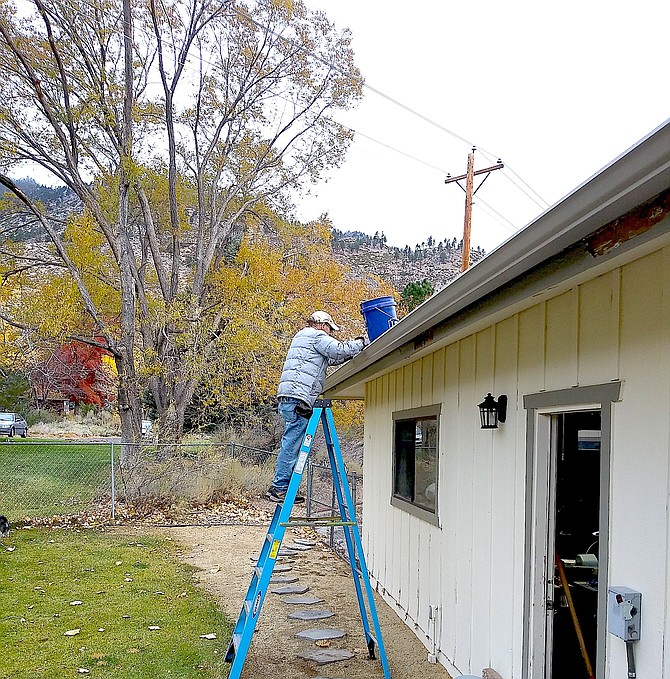 A Carson Valley resident cleans out the gutters in preparation for forecast heavy rain on Sunday.