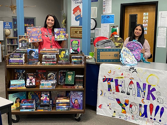 Fremont Librarian Rhiannon Moffat and Social Worker Paulina Hernandez display some of the books and backpacks provided by City National Bank.