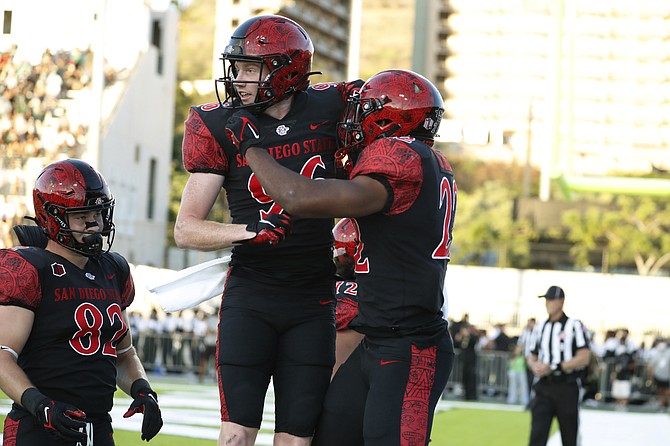 San Diego State tight end Jay Rudolph (82) and wide receiver Elijah Kothe (96) celebrate with running back Greg Bell (22) after Bell's touchdown against Hawaii on Nov. 6, 2021, in Honolulu. (AP Photo/Marco Garcia)