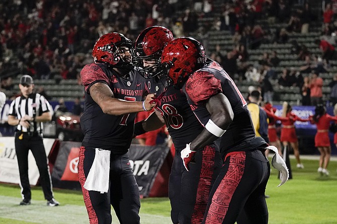 San Diego State tight end Daniel Bellinger, center, celebrates his touchdown with wide receiver Tyrell Shavers, right, and quarterback Lucas Johnson against Nevada on Nov. 13, 2021, in Carson, Calif. (AP Photo/Jae C. Hong)