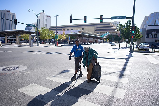 Downtown Reno Partnership ambassador Donald Griffin, left, helps a homeless person through a crosswalk at Evans and East 4th streets in Downtown Reno.