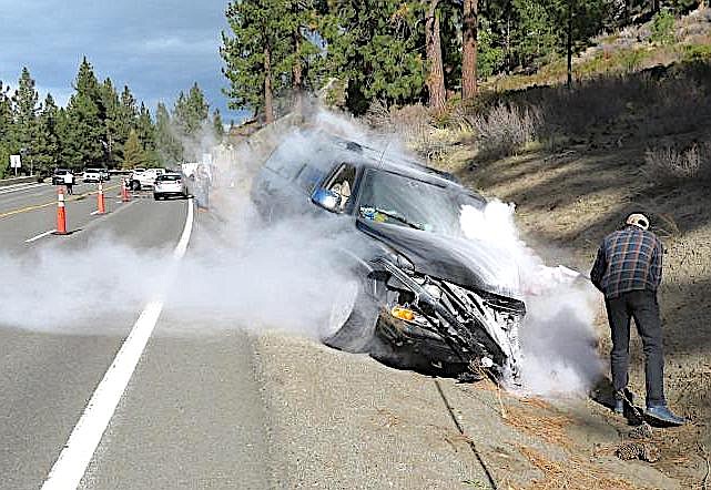 A passing motorist uses an extinguisher to put out a vehicle fire from a collision on Highway 50 on Friday morning. Bob Buehler photo