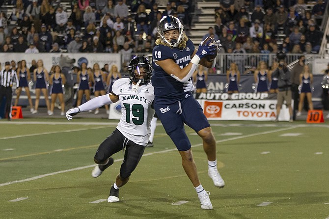 Nevada tight end Cole Turner makes a catch in front of Hawaii's Quentin Frazier during their game in Reno on Oct. 16, 2021. (AP Photo/Tom R. Smedes)