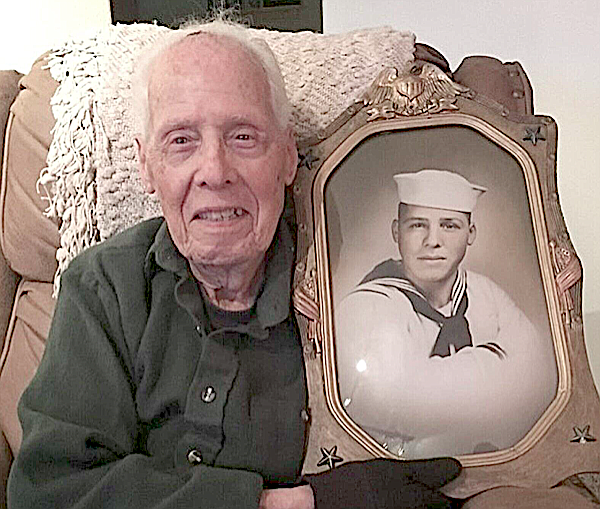 Gordon Ware with a photo from when he was a 19-year-old seaman.