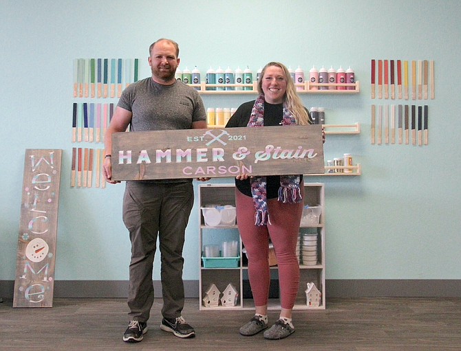 Michael Belardes and Melissa Feldman hold the sign to their new woodworking studio on Winnie Lane. (Photo: Faith Evans/Nevada Appeal)