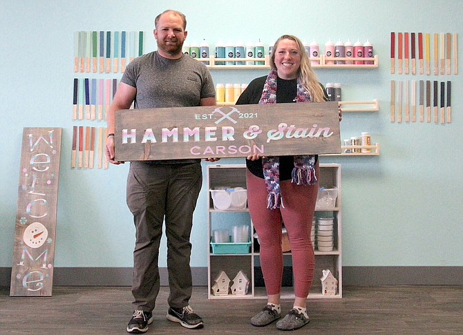 Michael Belardes and Melissa Feldman hold the sign to their new Hammer & Stain woodworking studio on Winnie Lane.
