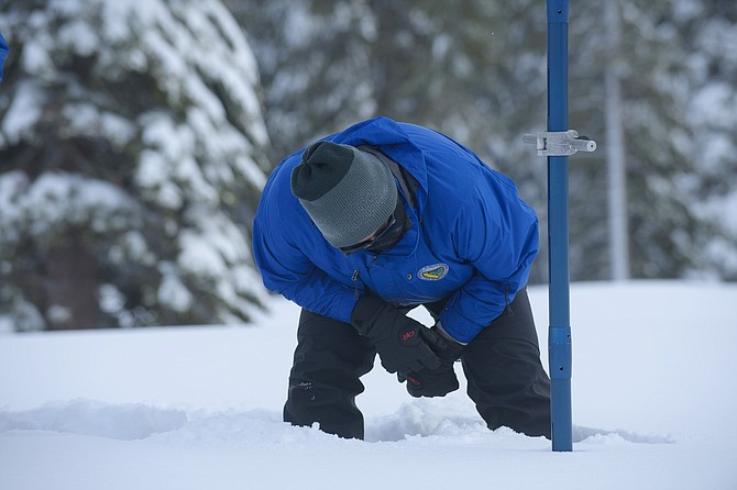 Sean de Guzman, chief of snow surveys for the California Department of Water Resources, checks the depth of the snow pack during the first snow survey of the season at Phillips Station near Echo Summit on Dec. 30, 2021. (AP Photo/Randall Benton)