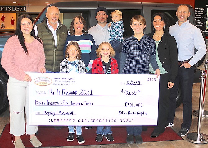 The Henning family displays this year’s total of $40,650 from the Pay It Forward program. Back row from left are Kurt, Debi, Clint (with Luke), Ember and Chris. Front row from left are Kamiah, Lili, Travis and Miles.