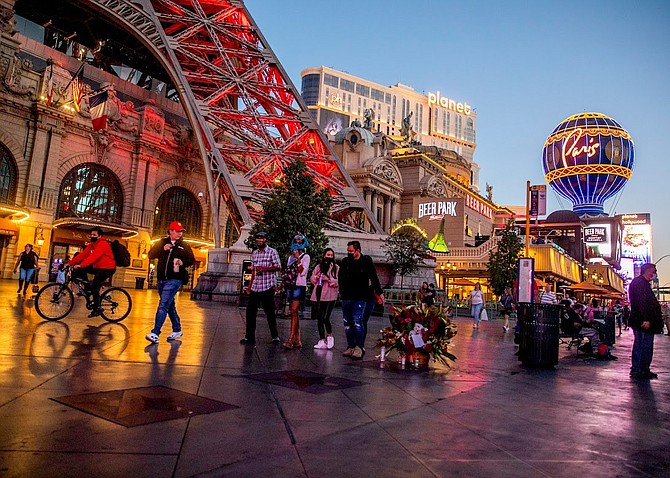 Pedestrians walk past Paris Las Vegas with Planet Hollywood in the background on Tuesday, Nov. 16, 2021.