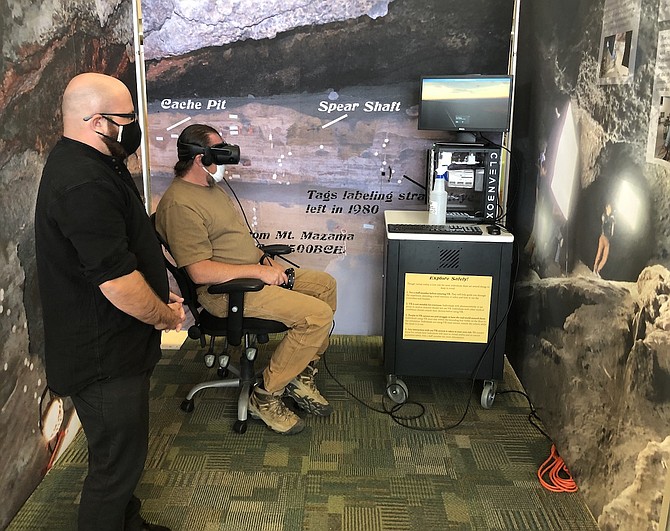Information Technology Librarian Joe Salsman assists a patron with the Hidden Cave VR experience.