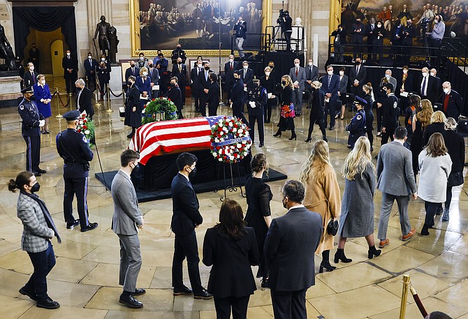 The family of former Senate Majority Leader Harry Reid of Nevada walks around his flag-draped casket as Vice President Kamala Harris and her husband, Douglas Emhoff, look on, during a memorial service for Reid in the Rotunda of the U.S. Capitol on Jan. 12, 2022, in Washington. (Evelyn Hockstein/Pool via AP)