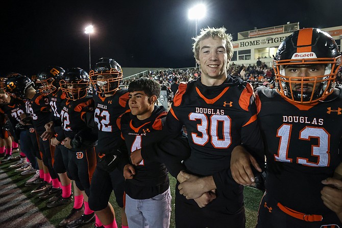 Douglas High’s Chris Smalley smiles while linked arm-in-arm with his Tiger football teammates during Senior Night.