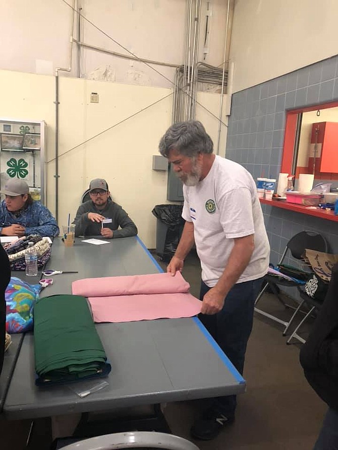 4-H volunteers cut fabric at sale.