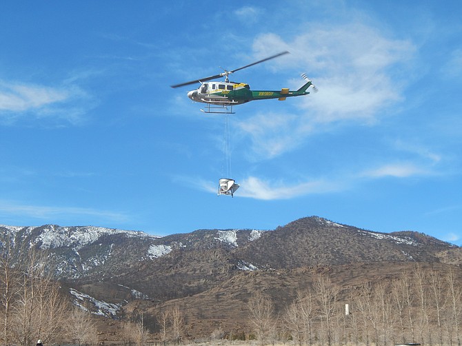 A Nevada Division of Forestry helicopter carries seed spreader over the Tamarack Fire burn scar in southern Douglas County.