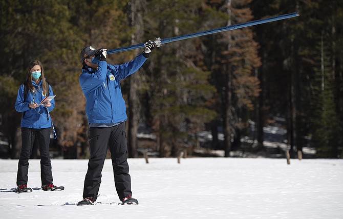 Lauren Alkire, left, and Sean de Guzman, manager of snow surveys and Water Supply Forecasting Unit, conduct the third snow survey of the season at Phillips Station near Echo Summit, Calif., on March 1, 2022. (Kenneth James/California Department of Water Resources via AP)