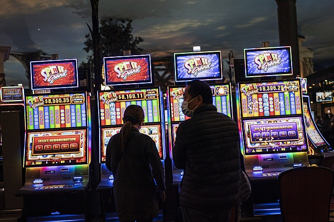 People stand in front of electronic slot machines in a casino in Las Vegas on Nov. 9, 2020. (Photo: Wong Maye-E/AP)