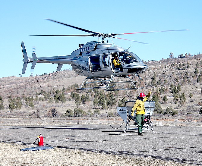 A helicopter picks up a bucket of seed for the next application near Indian Creek Campground in Alpine County. (Keith Barker photo)