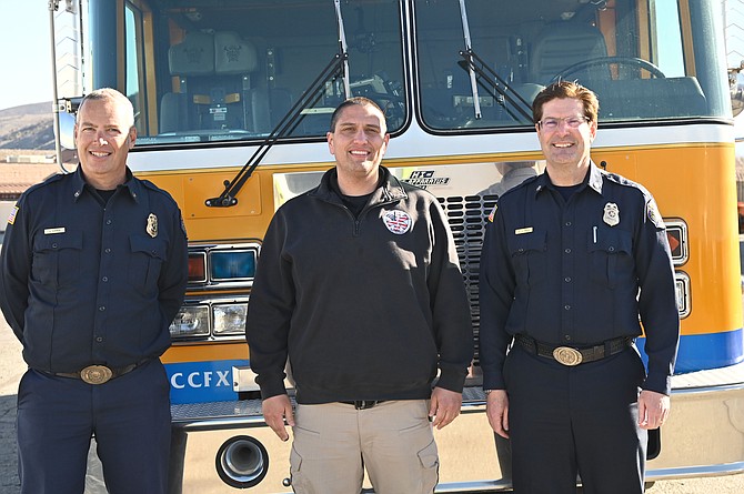 Battalion Chief Jason Danen, EMS/Paramedic Coordinator for WNC Terry Mendez, and Fire Chief Sean Slamon stand next to the donated fire engine.