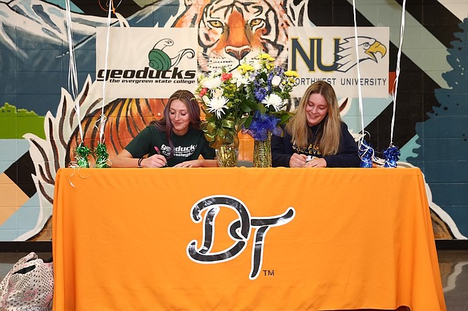 Douglas High seniors Marin Collins, left, and Riley Mello sign their respective Letters of Intent to play volleyball in college. Collins will be heading to Evergreen State College while Mello will play at Northwest University. Both schools play in the Cascade Collegiate Conference.