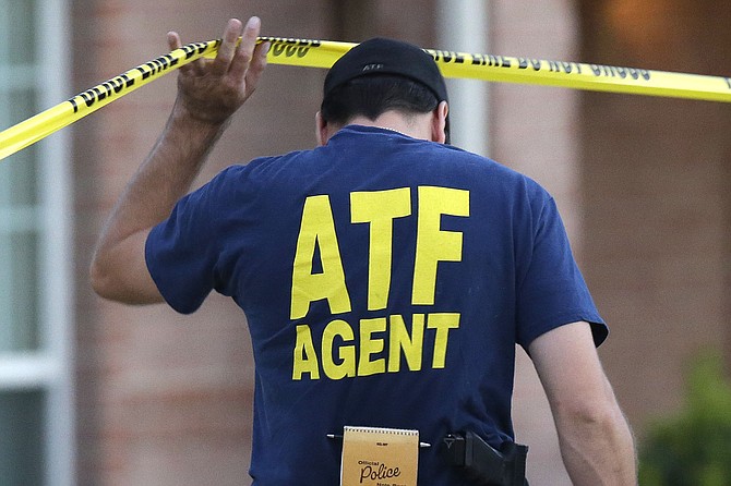 An ATF agent lifts crime scene tape, Aug. 8, 2013, in DeSoto, Texas.