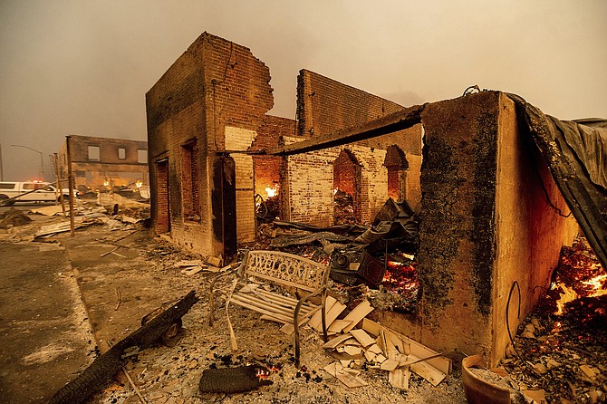 A bench stands outside a scorched building as the Dixie Fire tears through Greenville in Plumas County, Calif., on Aug. 4, 2021. The fire leveled multiple historic buildings and dozens of homes in central Greenville.