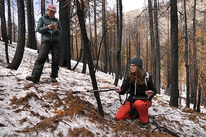 Graduate student Arielle Koshkin, left, takes notes as snow hydrologist Anne Nolin measures snow reflectivity at the site of the 2021 Caldor Fire on April 4, 2022, near Twin Bridges, Calif.