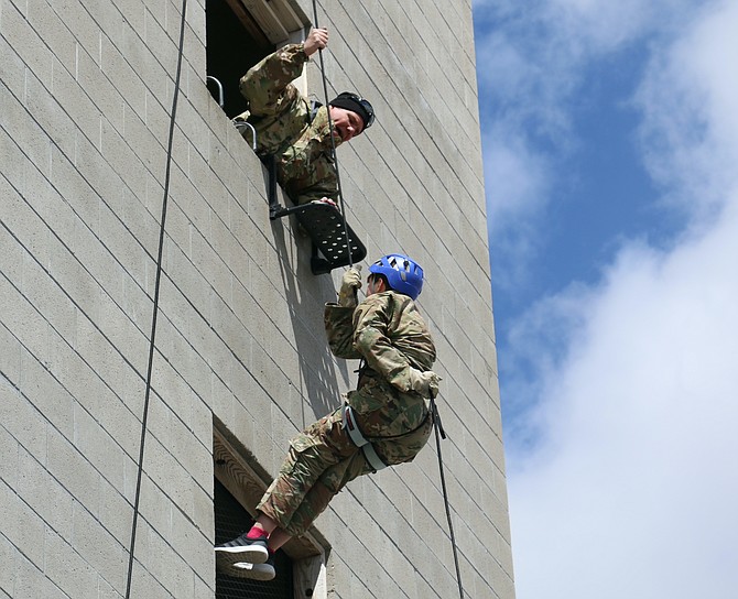 Sgt. 1st Class (ret.) Wes Gilleon, at top, looks down from the Lawrence Jacobsen Regional Fire Training Center tower Friday as Douglas High School cadet Harley Smith rappels down.
