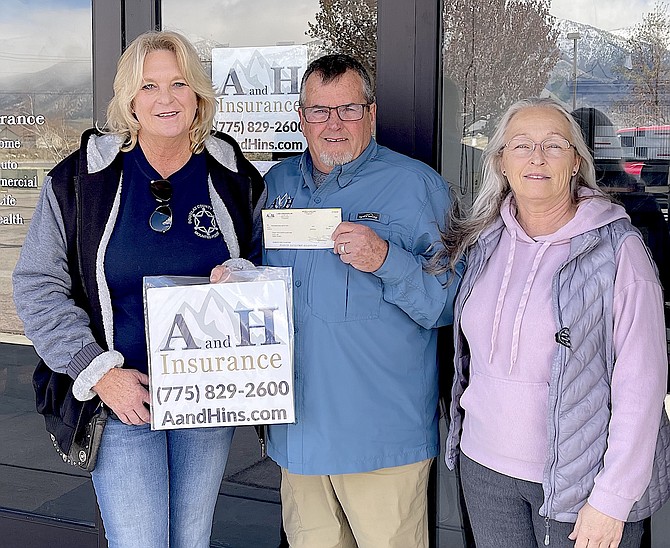 Douglas County Sheriffs Mounted Posse’s Mo Parga receives a $500 donation from George Swetland and Cindy Thomson of AandH Insurance.