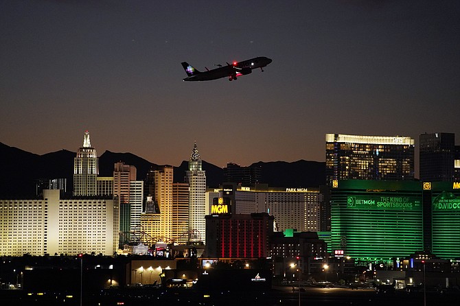 FILE - A plane takes off from Harry Reid International Airport near casinos along the Las Vegas Strip, on Sept. 29, 2021, in Las Vegas. Caesars Entertainment spinoff VICI Properties said April 29, 2022, that it completed its $17.2 billion buyout of MGM Growth Properties, the Las Vegas Review-Journal reported. The deal was first announced last August and included the assumption of about $5.7 billion of debt. (AP Photo/John Locher, File)