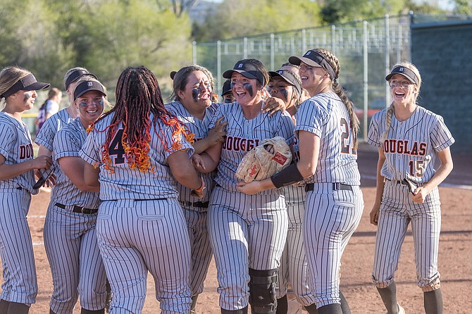 Talia Tretton (19) is mobbed by her teammates after Douglas High softball clinched a spot in the Class 5A state tournament Friday evening. Douglas will need to win one game Saturday to secure a Northern 5A regional crown.