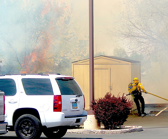 An East Fork firefighter battles a blaze behind the Douglas County Judicial & Law Enforcement Center in Minden.