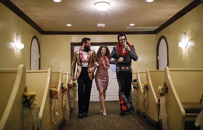 Elvis impersonator Brendan Paul, right, walks down the aisle during a wedding ceremony for Katie Salvatore, center, and Eric Wheeler at the Graceland Wedding Chapel in Las Vegas on Feb. 14, 2019.