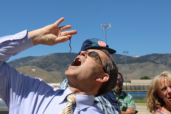Superintendent Richard Stokes dangles a worm over his mouth. The Greenhouse Project gifted him a bucket of worms to bring fishing when he retires in July.