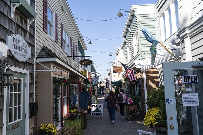 FILE - People walk by shops Nov. 13, 2020, in Rehoboth Beach, Del. The Friday June 10, 2022, report on consumer prices is expected to show that annual inflation slowed ever so slightly to 8.2% in May from 8.3% in the prior month. President Joe Biden faces a delicate trade-off as he tries to help his fellow Democrats in the upcoming midterm elections. He needs U.S. consumers to pull back just enough so that inflation eases, but not so much that the economy risks plunging into a recession. (AP Photo/Alex Brandon, File)