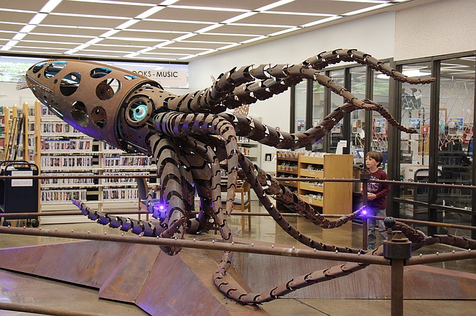 Theo Witos admires “Mechateuthis” at the Carson City library. The giant squid art installation will be in the lobby until Friday. Visitors can use the cranks along the railing to move the squid’s tentacles, beak, and fins.