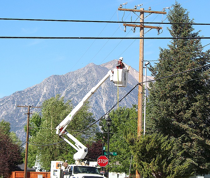An NV Energy electrician works on a pole on Second Street in Minden.