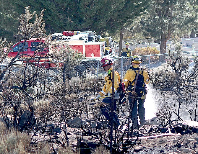 Firefighters hose down the site of a fire next to the Genoa Cemetery on June 17, 2022.