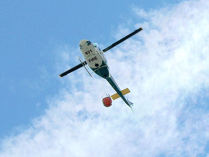A firefighting helicopter flies over Genoa on Friday evening.