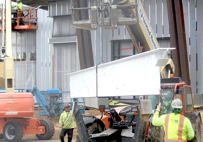 Workers guide a beam for the Events Center into the air on May 6. Supply shortages will delay completion of the biggest project in Douglas County until the second quarter of 2023.