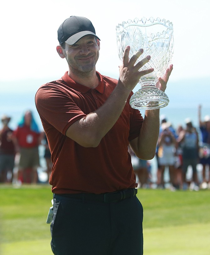 Tony Romo holds up the American Century Championship trophy on the 18th green after winning the 2022 ACC tournament Sunday. Romo did so on the second playoff hole ousting Joe Pavelski and Mark Mulder, who were all tied at the end of the final round.