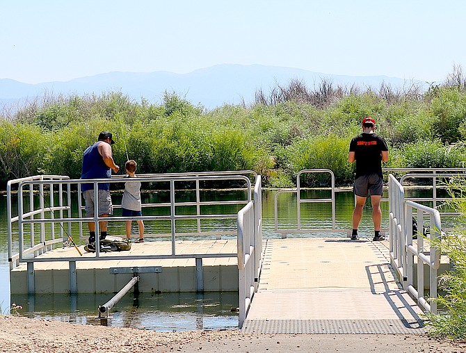 Anglers drop a line off the dock at the Seeman Ranch Park pond on Wednesday.