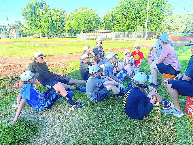 12U team members listen to their coaches after practice on Thursday.