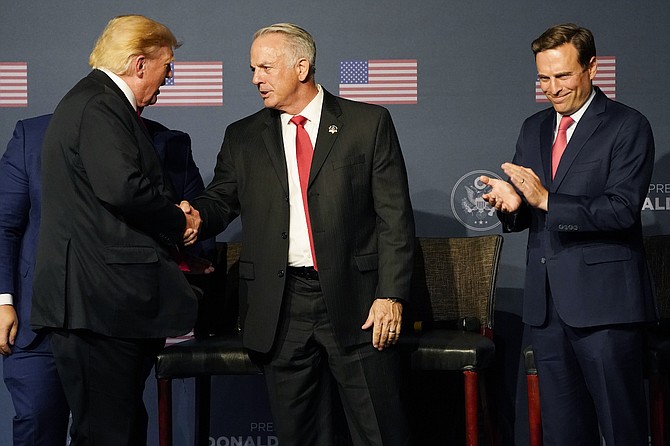 Former President Donald Trump, left, shakes hands with Joe Lombardo, Clark County sheriff, next to Adam Laxalt, right, during an event July 8, 2022, in Las Vegas.