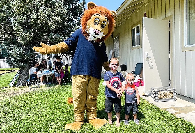 Legacy Christian Academy’s Lewis the Lion stands with Benjamin Walker, 4, and his brother Levite Walker, 1, July 24 at the school’s open house event. Leeann Walker of Carson City, the boys’ mother, was looking forward to enrolling Benjamin this year in the school.