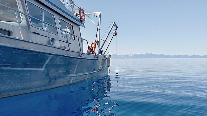 The University of California Davis Tahoe Environmental Research Center’s Katie Senft lowers a Secchi disk to measure lake clarity in June 2021. Researchers take dozens of such measurements throughout each year.