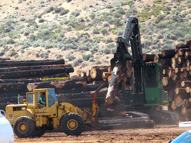 Workers stack salvaged wood from the Caldor Fire on a site behind Carson Valley Plaza just west of Vista Grande on Wednesday.